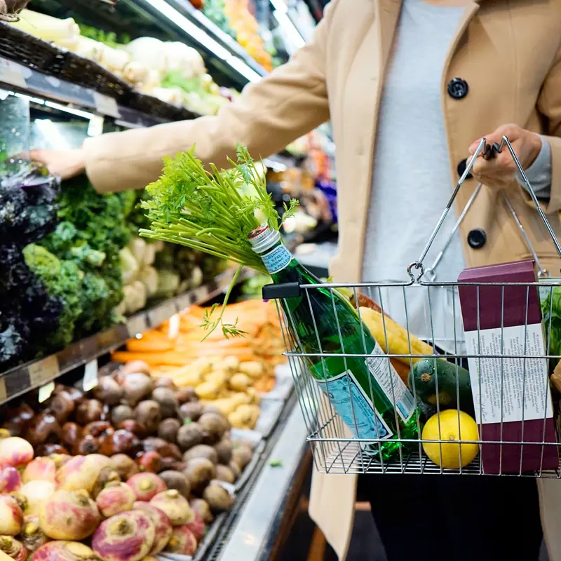 A shopper with a wire basket in the produce aisle