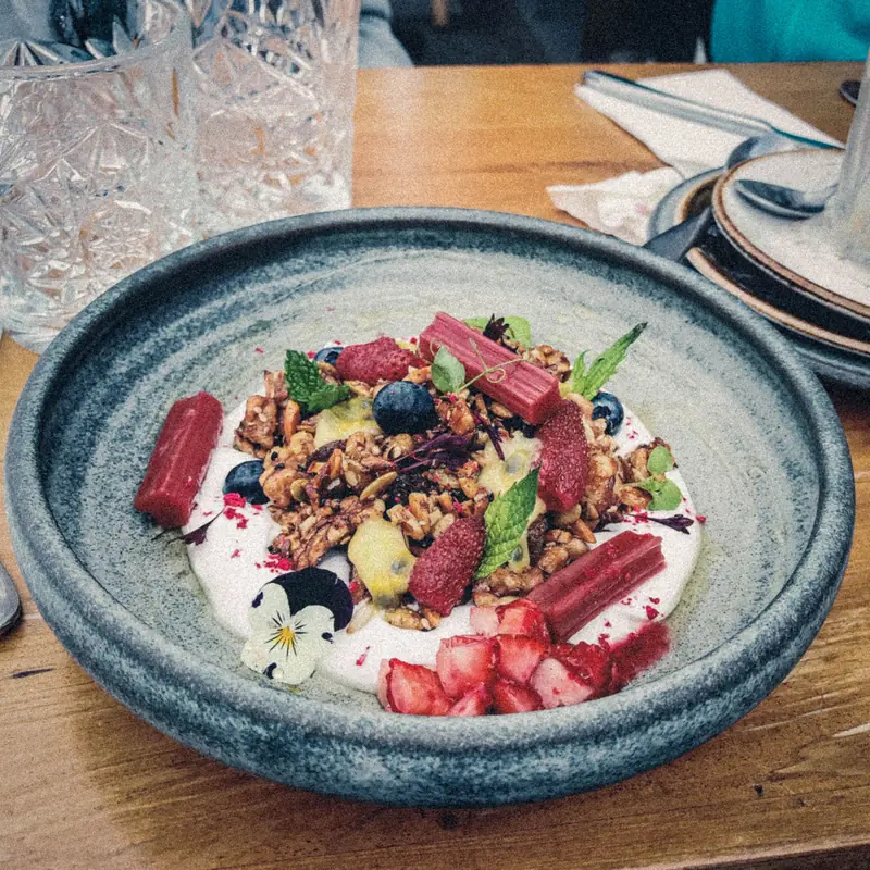 Yoghurt, granola and fruit in a dark ceramic bowl